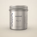 A silver metal supplement jar labeled MAIOME No.11, photographed against a clean, solid, warm off-white background.